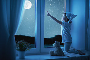 Kleines Kind nachts am Fenster