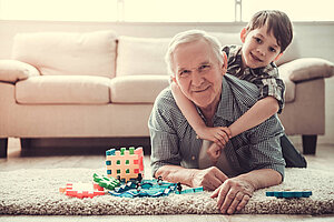 Opa spielt mit Enkel im Wohnzimmer